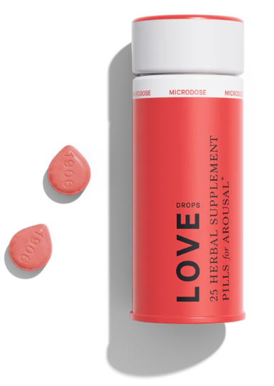 A minimalist studio product photograph on a clean white background. It features a vertical red cylindrical canister with a white lid labeled "LOVE DROPS 25 HERBAL SUPPLEMENT PILLS for AROUSAL." The white band near the top repeats the word "MICRODOSE." To the left of the upright bottle, two pinkish-red teardrop-shaped pills stamped with "1906" lie flat, casting soft shadows.